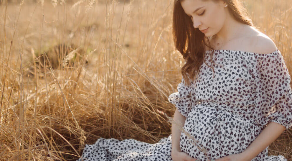 Pregnant woman sitting at the field